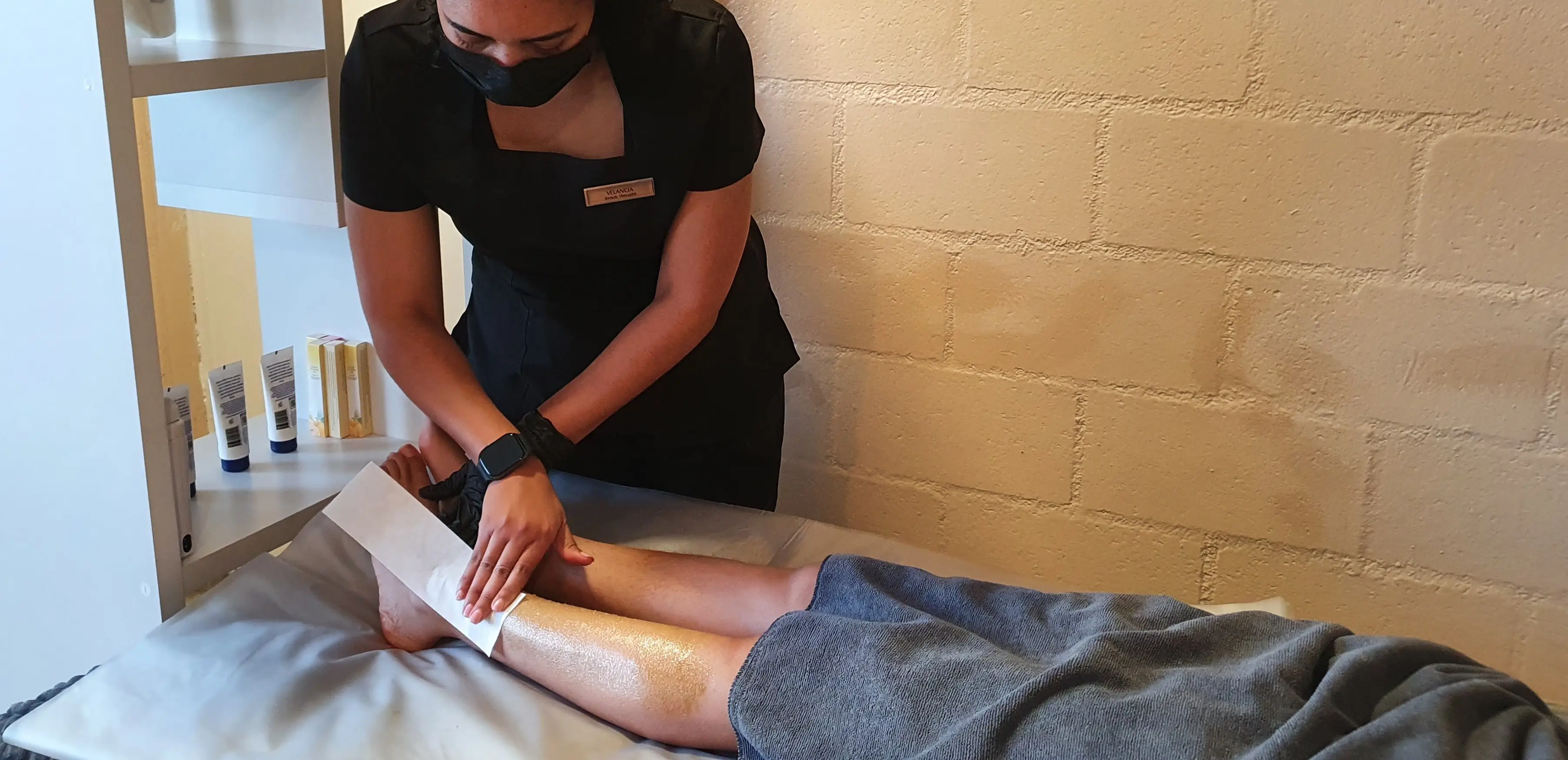beauty therapist waxing a client's leg.