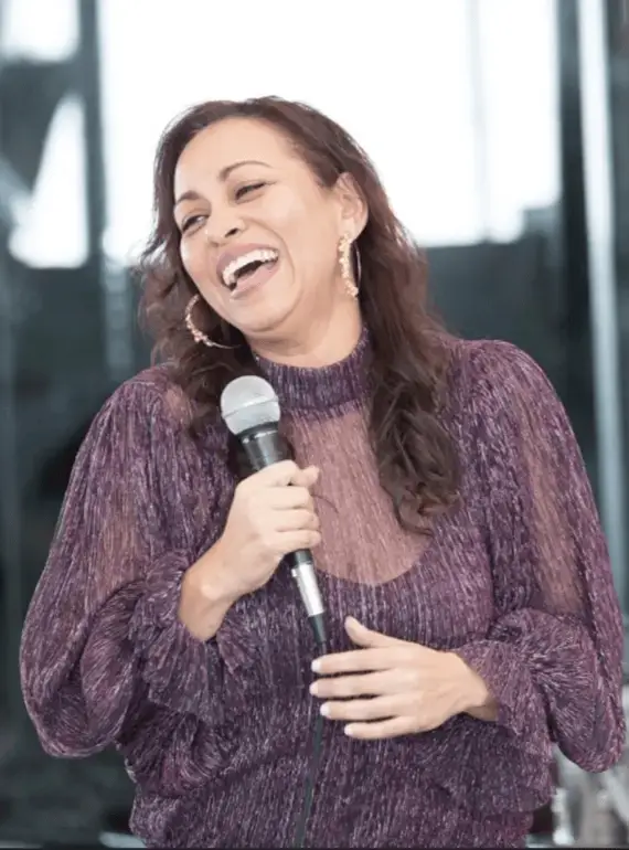 A smiling woman holding a mic